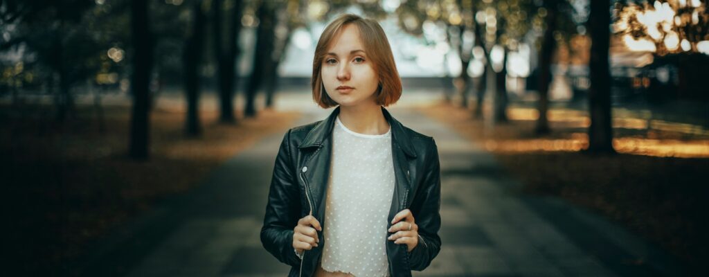 Young woman in leather jacket standing in park